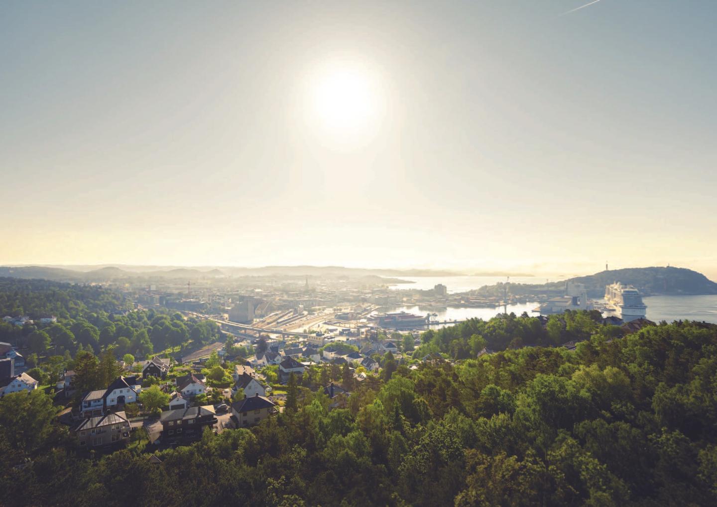 Flyfoto av Kristiansand som viser Gartnerlökka-området, hvor Ramboll transformerer E18/E39-korridoren for å koble byutvikling med omkringliggende natur og kystlinje.